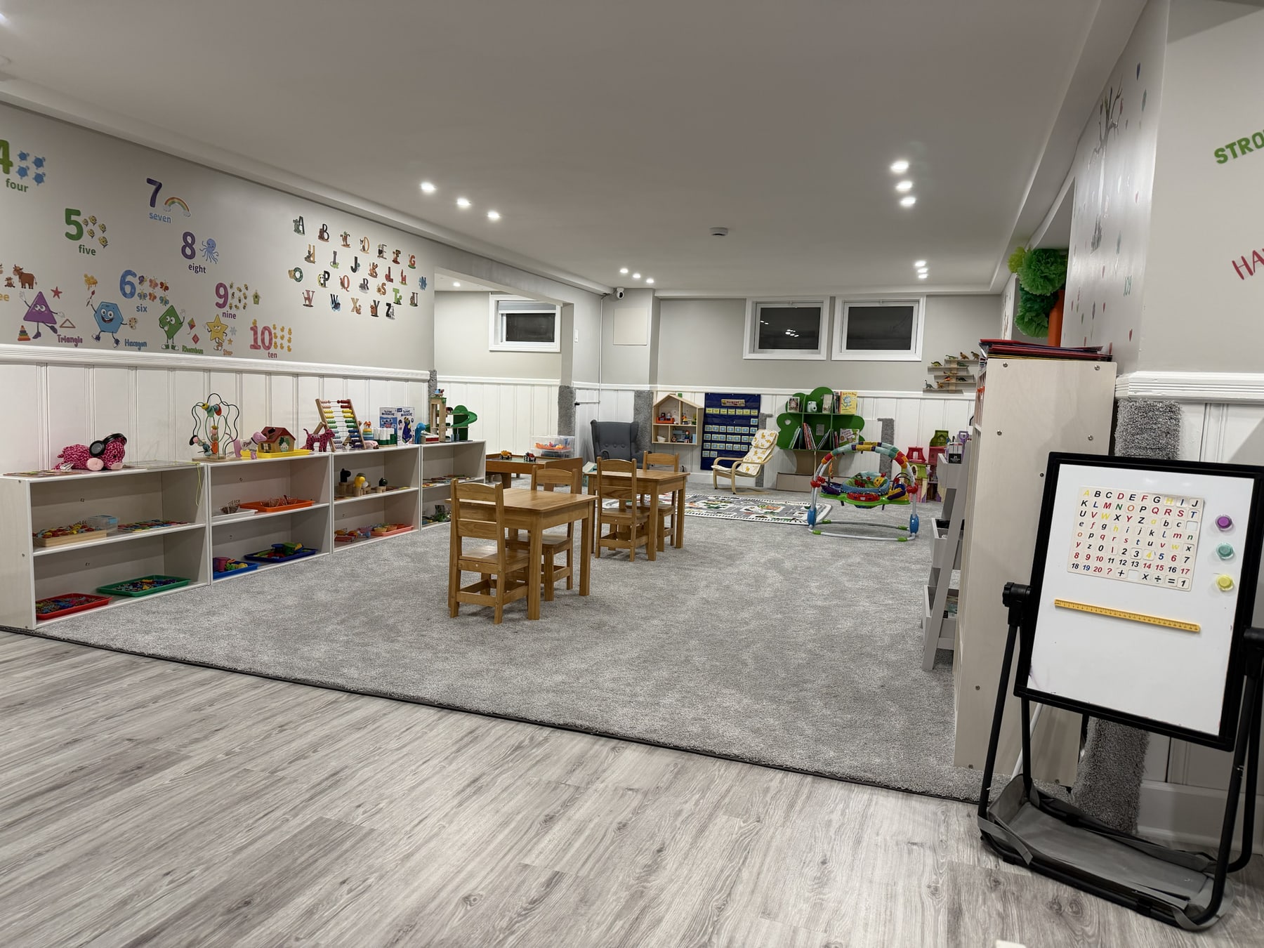 A wide view of the actual Bluebird Learning Nest activity room with child-sized tables, organized materials, and open space for play